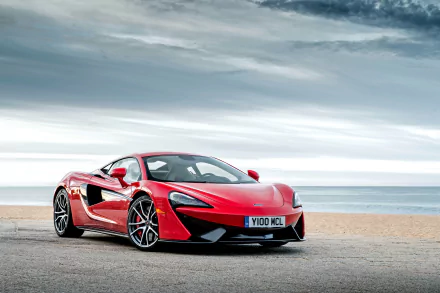 A stunning McLaren 570S sports car in vibrant red parked by the beach, set against a dramatic sky, captured in a 4K Ultra HD desktop wallpaper.
