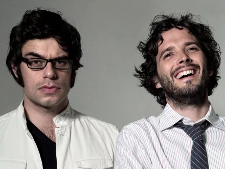 HD PC desktop wallpaper featuring the musical comedy duo Flight of the Conchords, with one member wearing glasses and the other smiling.