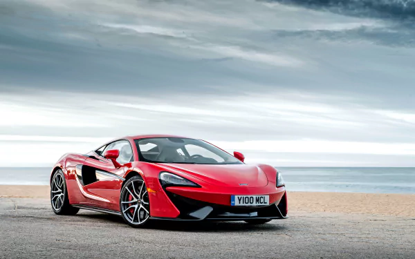 A stunning McLaren 570S sports car in vibrant red parked by the beach, set against a dramatic sky, captured in a 4K Ultra HD desktop wallpaper.
