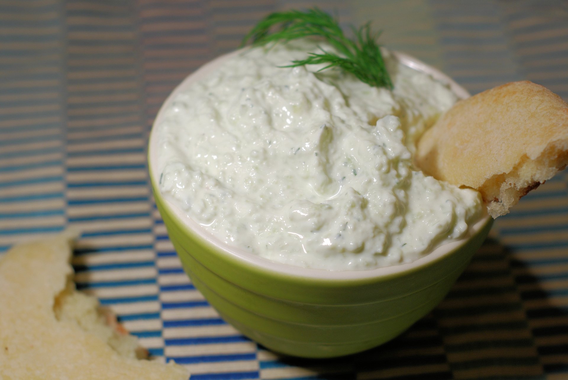 4K Ultra HD PC desktop wallpaper/background: close-up of creamy tzatziki in a green bowl, garnished with dill and a torn pita on a striped placemat.