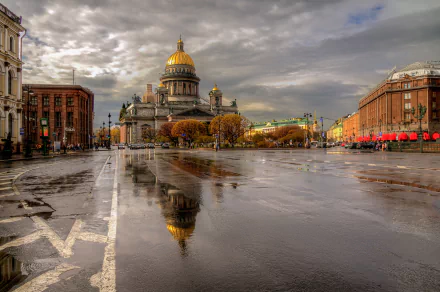 A stunning view of Saint Petersburg showcases a grand building reflected in a wet street, capturing the city's unique architecture and atmosphere under a dramatic sky.