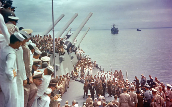 4K Ultra HD desktop wallpaper of the battleship USS Missouri (BB-63) at sea, military crew assembled on deck as the warship sails toward distant vessels under a calm sky.