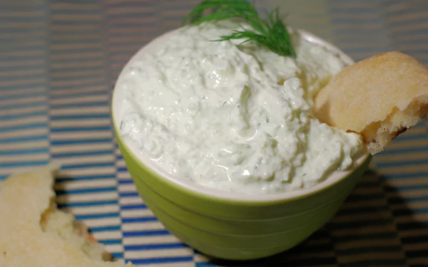4K Ultra HD PC desktop wallpaper/background: close-up of creamy tzatziki in a green bowl, garnished with dill and a torn pita on a striped placemat.