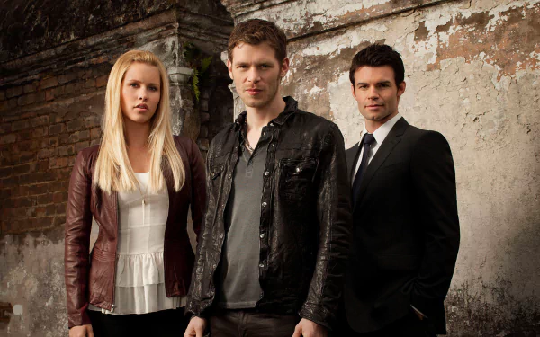 Three main characters from the TV show *The Originals* stand against a weathered wall. The image serves as a high-definition desktop wallpaper featuring a dramatic, moody backdrop.
