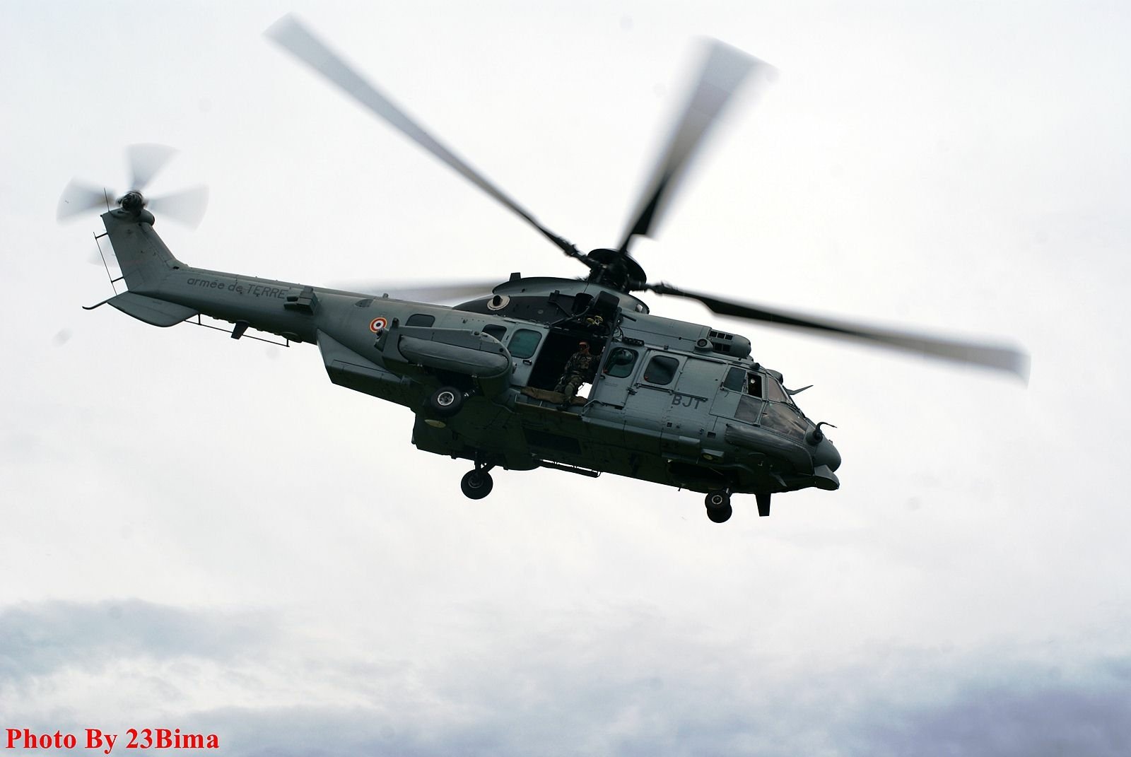 HD desktop wallpaper featuring a military helicopter in flight against a cloudy sky.