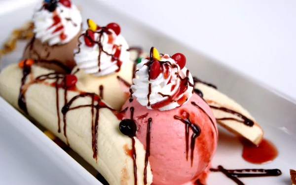 4K Ultra HD PC desktop wallpaper and background of a banana split: scoops of ice cream with whipped cream, cherries, chocolate drizzle and sliced banana on a white dish.