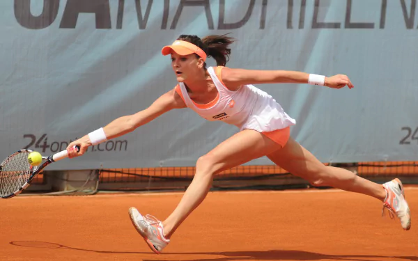 Female Polish tennis player lunging on a clay court in dynamic sports action — 4K Ultra HD PC desktop wallpaper.
