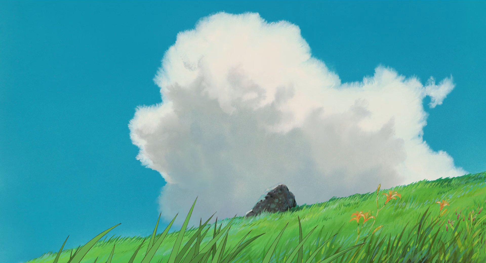 HD PC desktop wallpaper featuring a serene Anime scene from Spirited Away with lush green grass, small orange flowers, and a bright blue sky with fluffy white clouds.