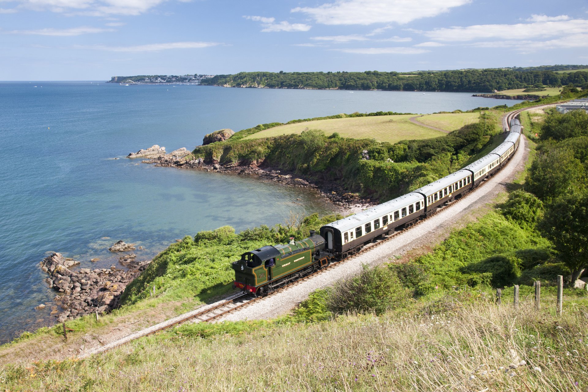 5K Ultra HD PC desktop wallpaper and background: vintage steam train (vehicle, train) winding along coastal cliffs with green fields and blue sea under a sunny sky.