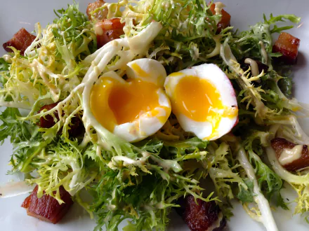 Close-up of a Salade Lyonnaise with a soft-boiled egg, frisée greens, and bacon, captured in HD for a vibrant lunch meal desktop wallpaper.