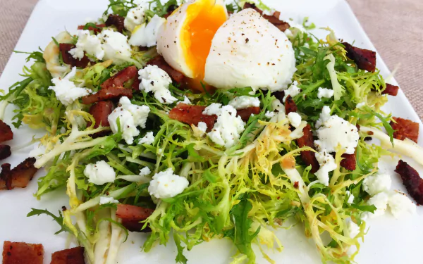 A vibrant Salade Lyonnaise featuring frisée greens, crispy bacon, crumbled cheese, and a soft-boiled egg, presented as an HD PC desktop wallpaper background.