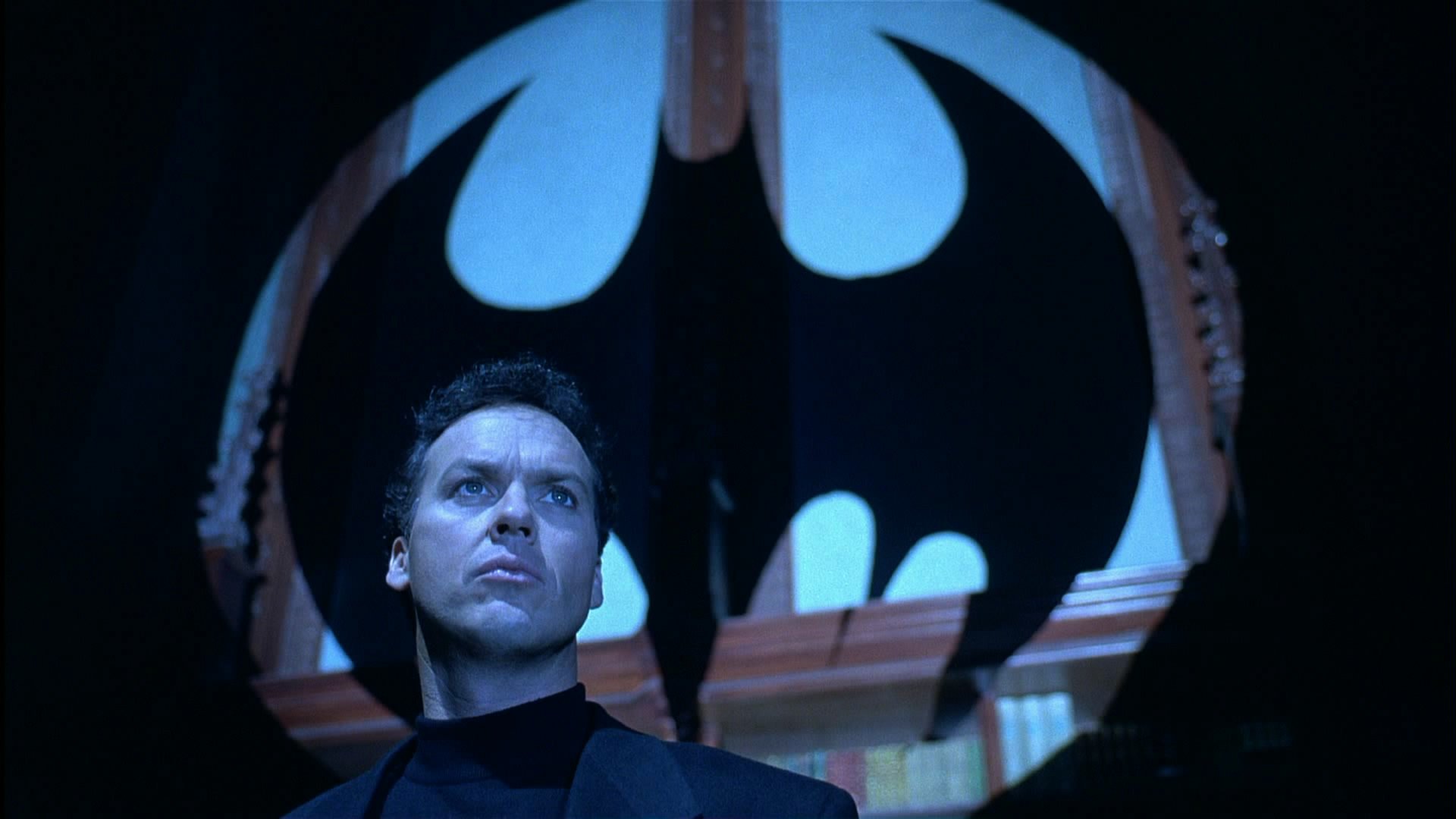 HD PC desktop wallpaper: an actor as Batman stands beneath a giant bat emblem, scene from the movie Batman Returns.