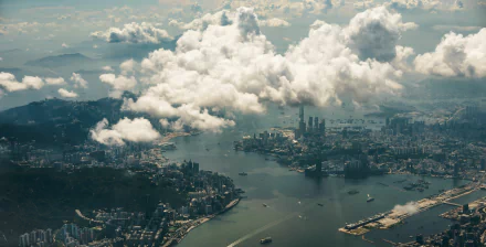A stunning HD aerial view of Hong Kong, showcasing the cityscape beneath scattered clouds. This desktop wallpaper captures the dynamic blend of nature and man-made structures in this vibrant metropolis.