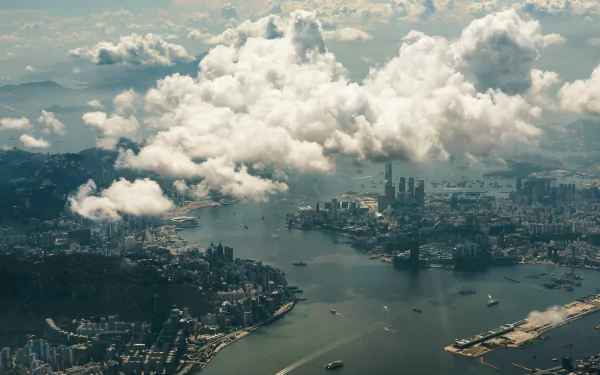 A stunning HD aerial view of Hong Kong, showcasing the cityscape beneath scattered clouds. This desktop wallpaper captures the dynamic blend of nature and man-made structures in this vibrant metropolis.
