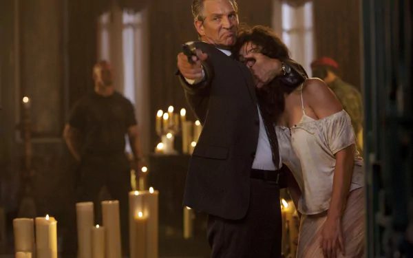 Scene from The Expendables featuring Eric Roberts as Monroe, holding a gun with Giselle Itié’s character Sandra in a tense moment, surrounded by dim candlelight.