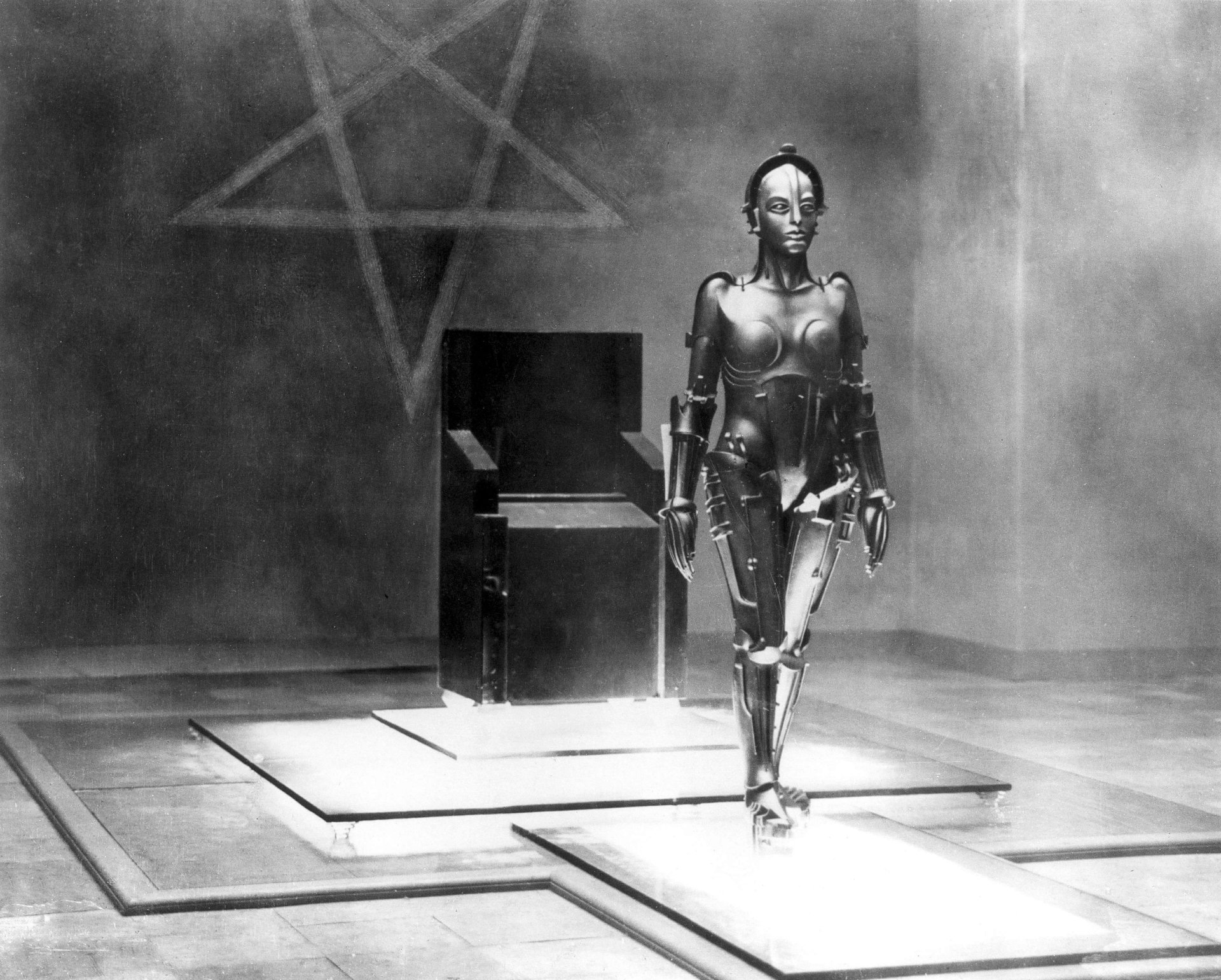 Black-and-white movie still from Metropolis: a female robot strides across an industrial stage — 2K Quad HD PC desktop wallpaper and background.