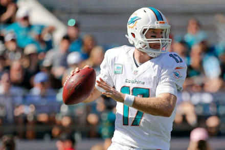 HD PC desktop wallpaper background: Miami Dolphins quarterback in white uniform drops back to pass on the field, blurred crowd behind — sports action shot.