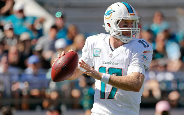 HD PC desktop wallpaper background: Miami Dolphins quarterback in white uniform drops back to pass on the field, blurred crowd behind — sports action shot.