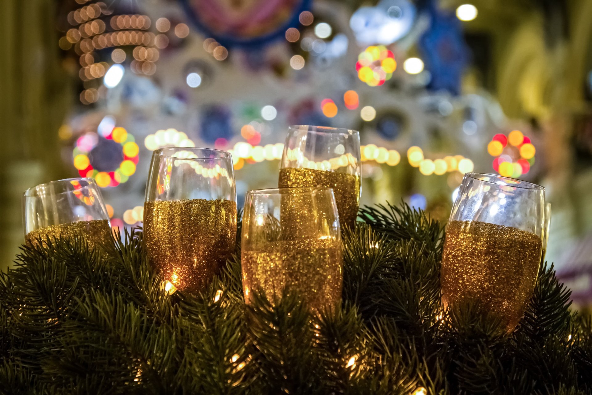 HD desktop wallpaper featuring sparkling champagne glasses surrounded by holiday greenery, capturing a festive New Year celebration atmosphere with vibrant lights.