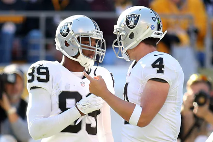 HD PC desktop wallpaper: two Las Vegas Raiders players in white uniforms conversing on the sideline during a sports game, stadium crowd background.