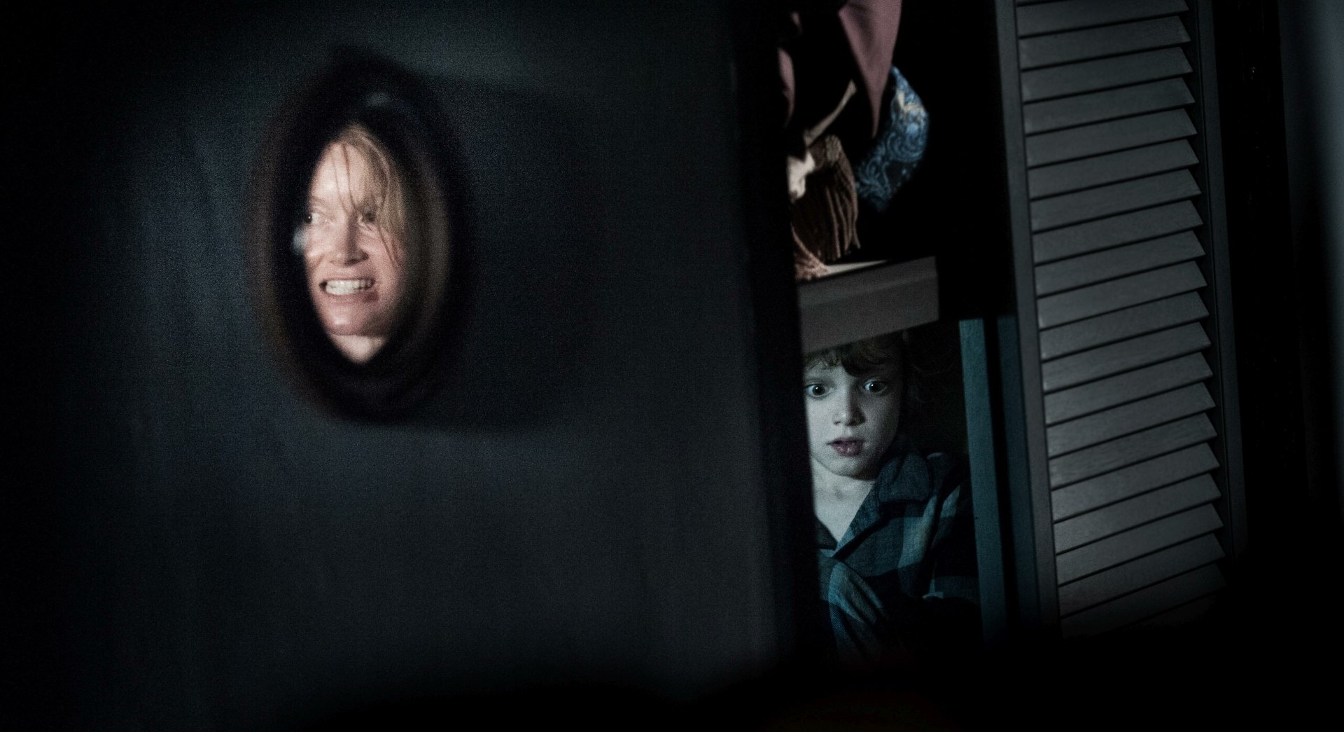 HD PC desktop wallpaper from the movie The Babadook, featuring a frightened woman’s face reflected in a door’s peephole and a child peering from behind a closet.