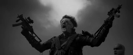 HD PC desktop wallpaper from Mad Max: Fury Road: a blindfolded, armored man screams with arms raised, ammo belts across his chest against a brooding, stormy sky background.