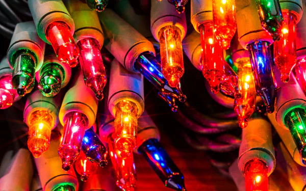 Close-up of colorful Christmas string lights aglow, festive holiday glow and bokeh — 5K Ultra HD PC desktop wallpaper/background.