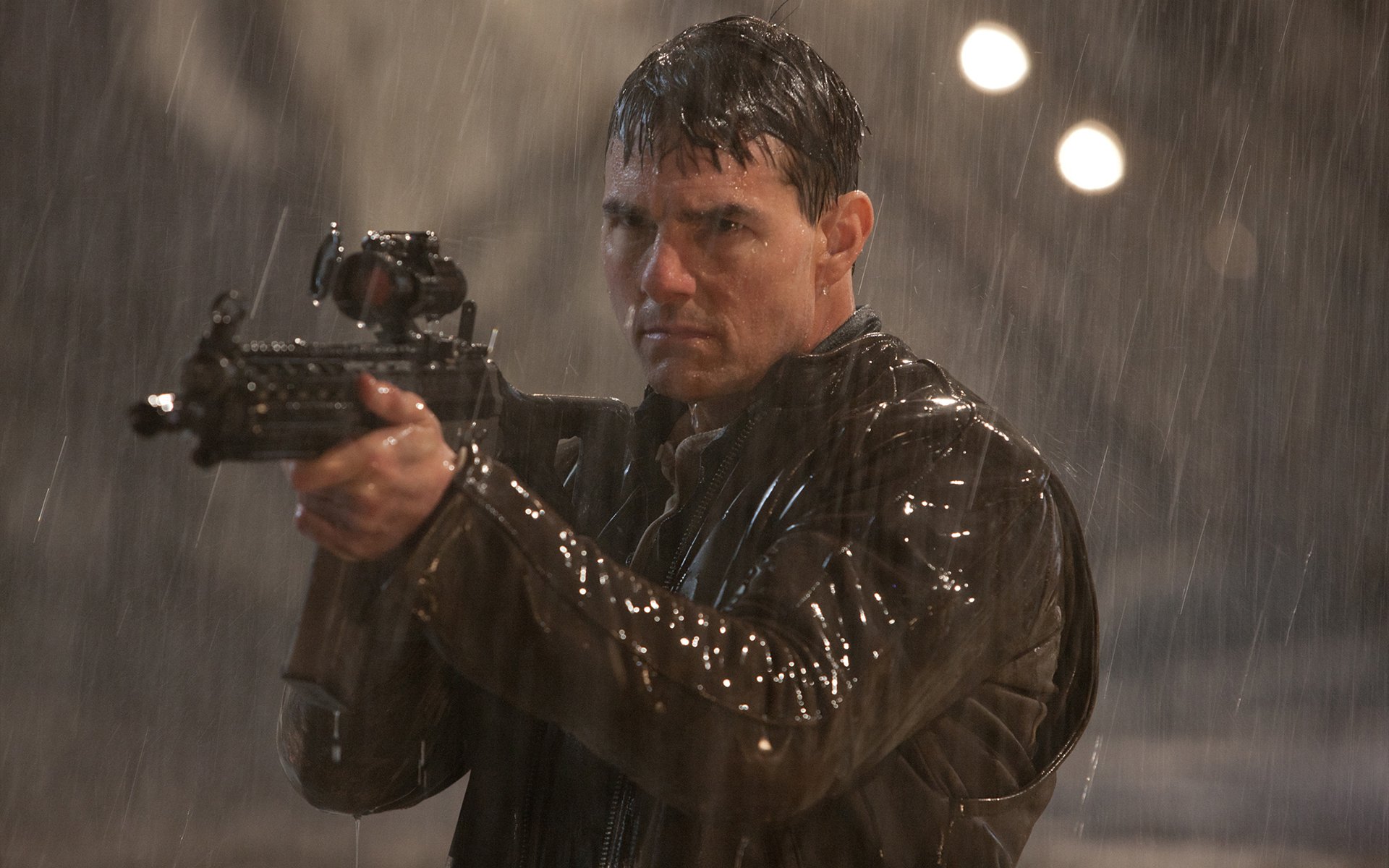 HD desktop wallpaper featuring Tom Cruise as Jack Reacher aiming a firearm in the rain, capturing an intense movie scene.