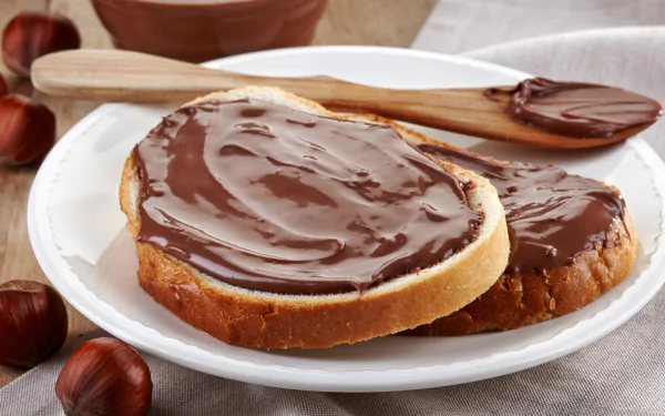 Two slices of bread spread with creamy Nutella hazelnut chocolate on a white plate, captured in high-definition for a food dessert-themed PC desktop wallpaper.