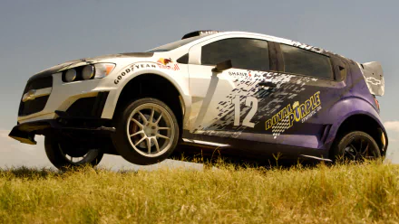 A dynamic HD wallpaper featuring a race car from the movie Transformers: Age of Extinction, showcasing its vibrant design against a grassy backdrop.