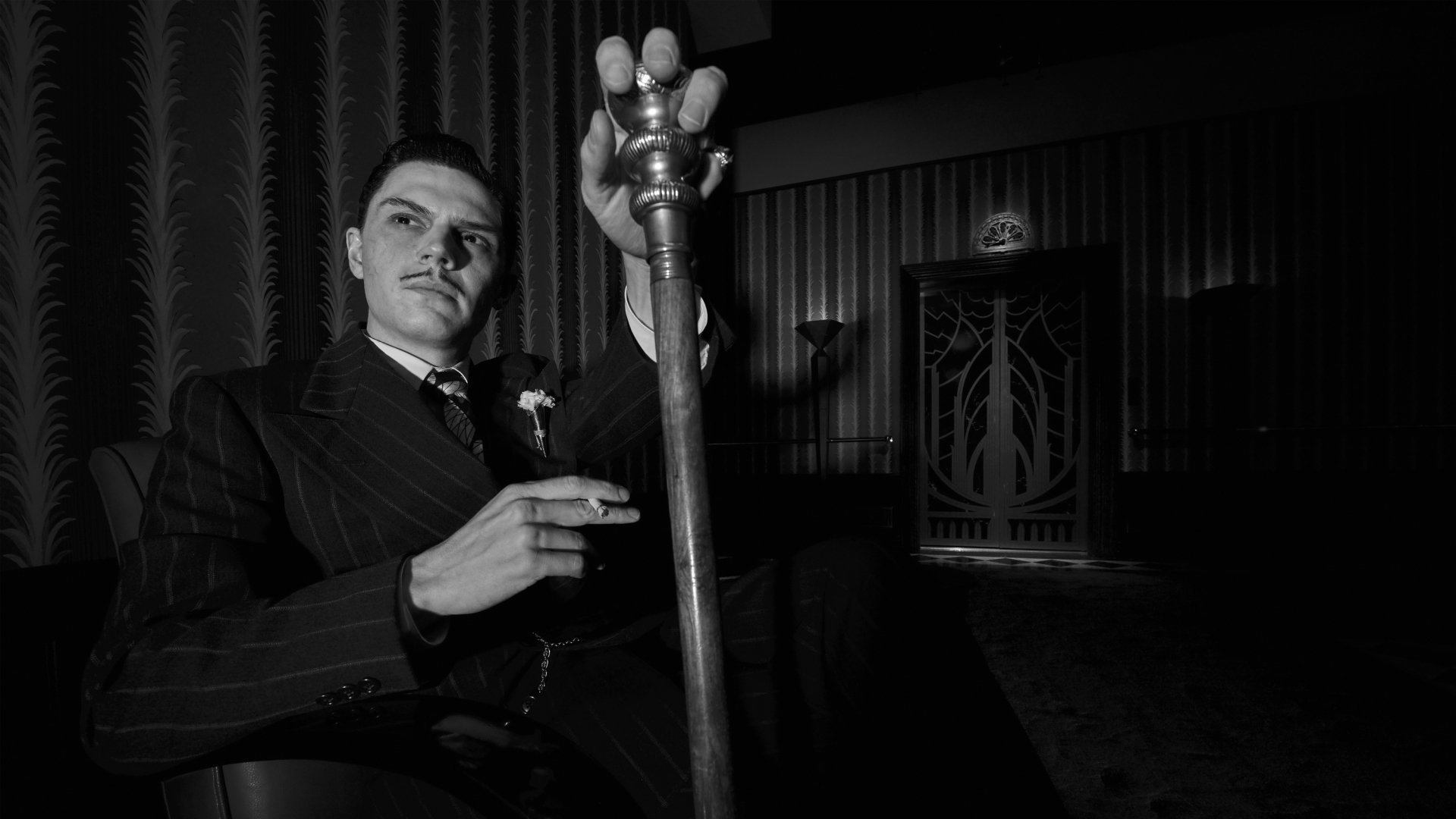 Black and white HD desktop wallpaper featuring a character from the TV show American Horror Story, sitting with a cane in a dimly lit, vintage-style room.