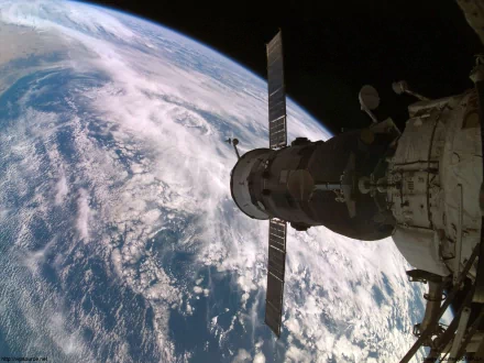 HD PC desktop wallpaper showing a NASA spacecraft orbiting above Earth, capturing the planet's cloud patterns and curvature in a man-made space structure view.