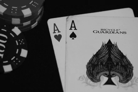 Black & white 4K Ultra HD poker scene featuring a pair of aces from Bicycle Guardians deck and stacked poker chips on a glossy surface.