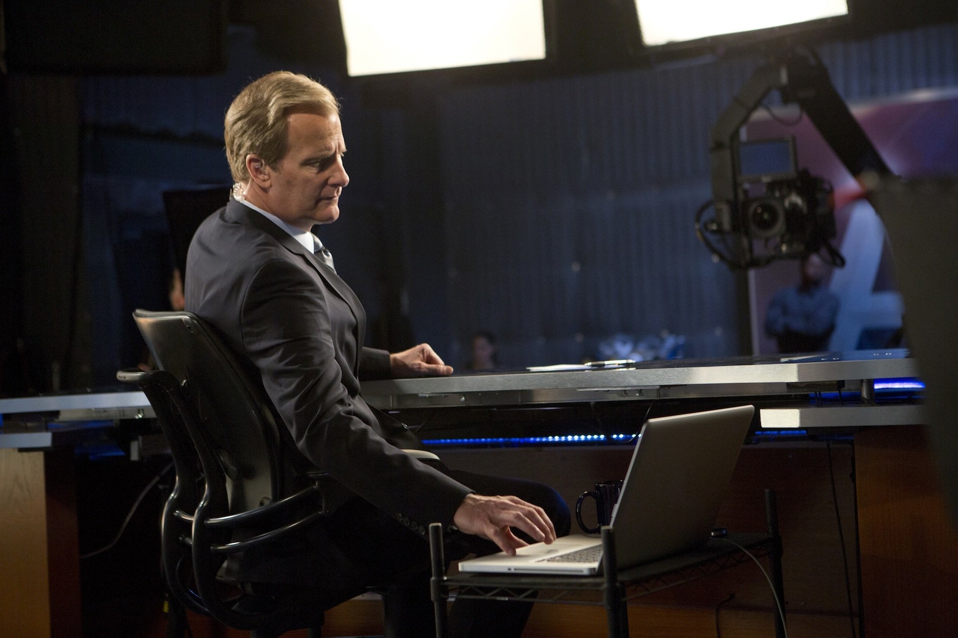 HD desktop wallpaper from The Newsroom (2012) featuring a man at his desk in a studio setting, poised for a broadcast.