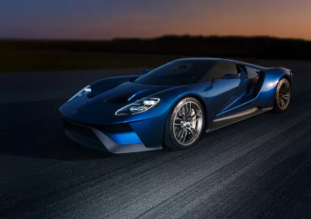 A sleek blue Ford GT supercar captures attention on a dark track, showcasing its dynamic design and high-performance features in this stunning HD desktop wallpaper.