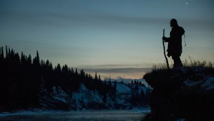 HD PC desktop wallpaper depicting a silhouetted figure with a staff overlooking a snowy river valley at dusk, inspired by the movie The Revenant.