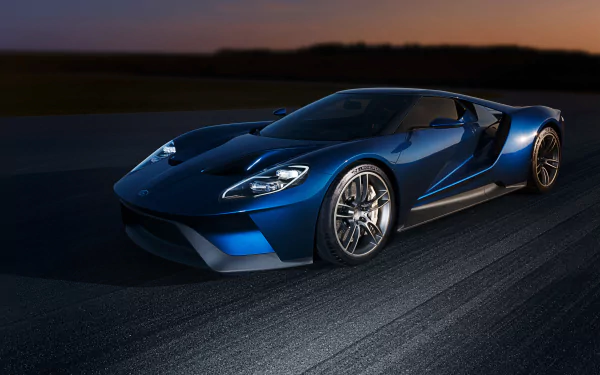 A sleek blue Ford GT supercar captures attention on a dark track, showcasing its dynamic design and high-performance features in this stunning HD desktop wallpaper.