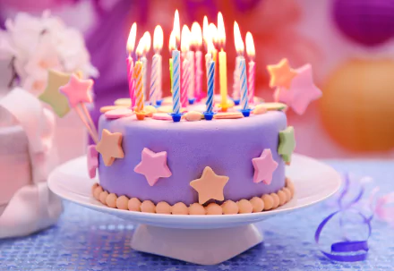 HD desktop wallpaper featuring a colorful birthday cake adorned with lit candles and star-shaped decorations, set against a festive background.