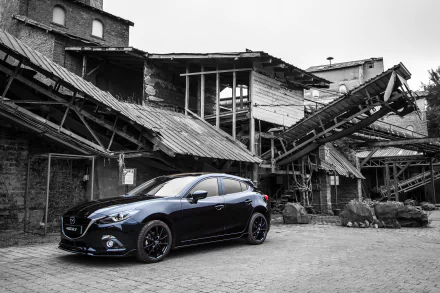 Black Mazda 3 hatchback vehicle parked in front of a dilapidated industrial building — 4K Ultra HD desktop wallpaper background.