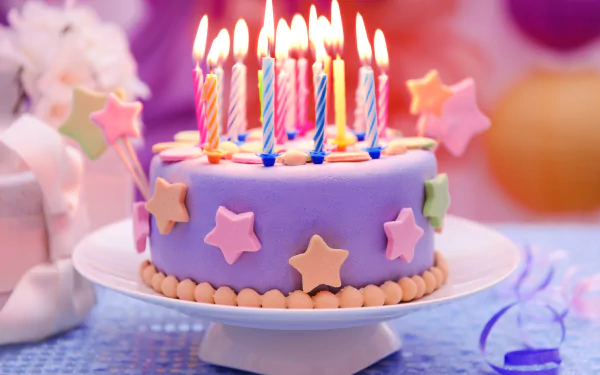 HD desktop wallpaper featuring a colorful birthday cake adorned with lit candles and star-shaped decorations, set against a festive background.