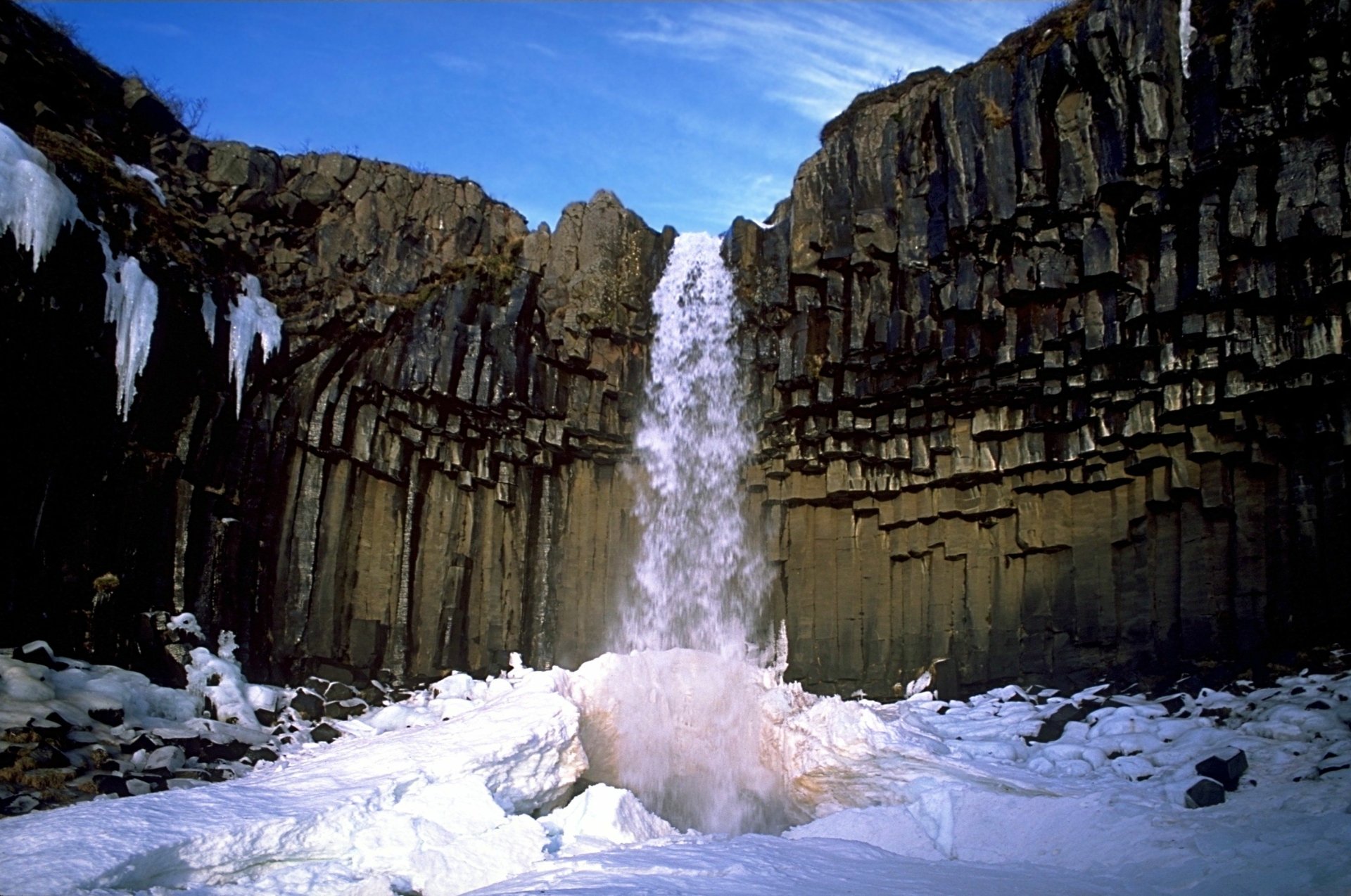 Svartifoss waterfall amid hexagonal basalt columns and snow under a clear blue sky — nature scene, 2K Quad HD PC Desktop Wallpaper and Background.