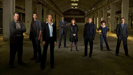 HD PC desktop wallpaper featuring the main cast of the TV show Fringe standing in a dimly lit, abandoned industrial space.