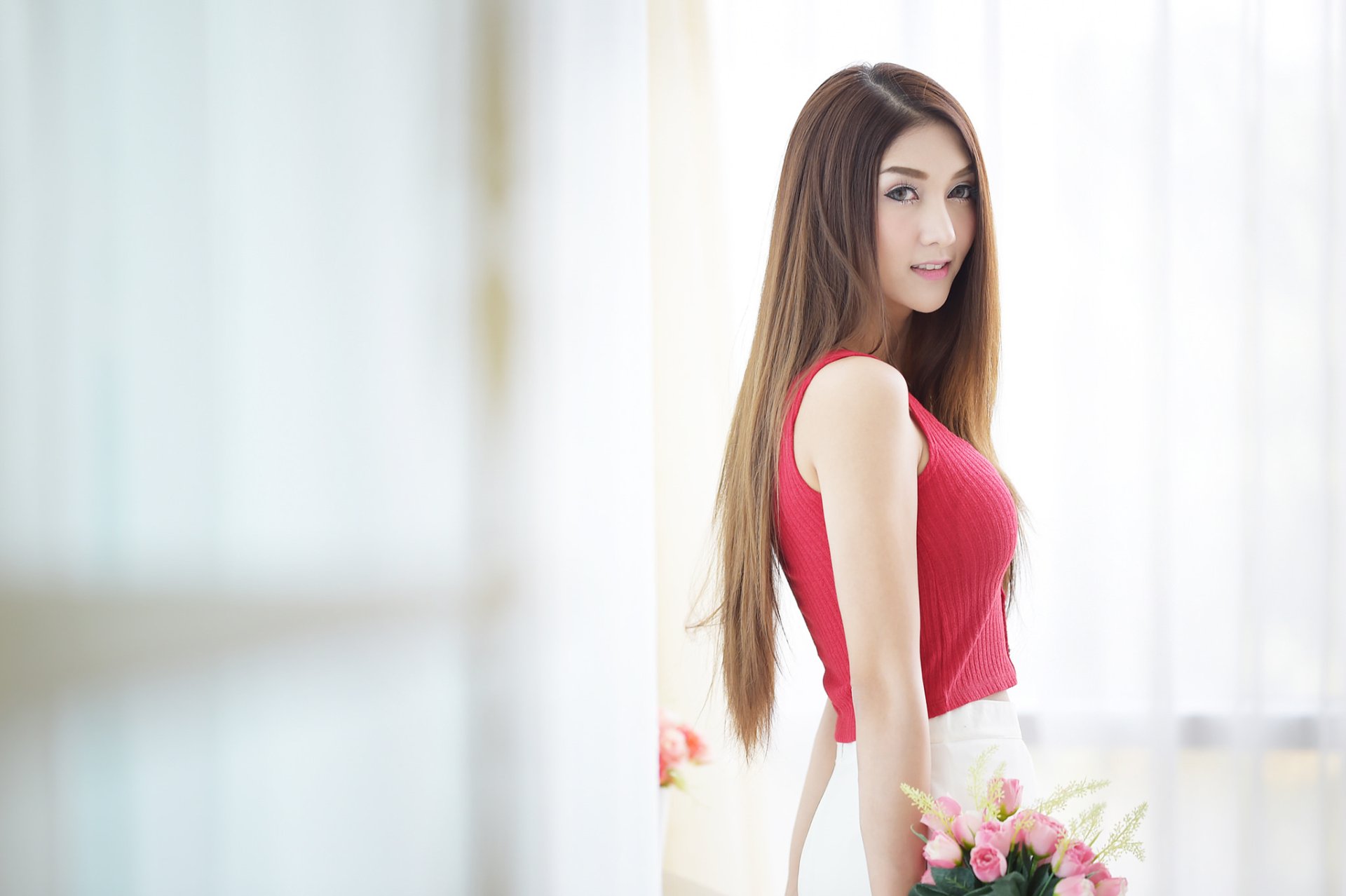HD desktop wallpaper featuring an Asian brunette woman, wearing a red top, holding flowers in soft bokeh background.