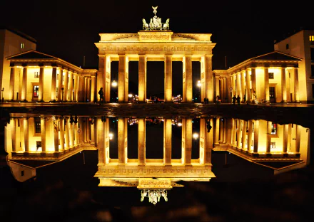 A stunning night view of Berlin's Brandenburg Gate, illuminated and reflecting beautifully in a puddle, showcasing the monument's grandeur in Germany's vibrant capital.