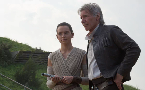 Harrison Ford as Han Solo and Daisy Ridley as Rey stand together in a scene from Star Wars Episode VII: The Force Awakens, set against a lush green backdrop.