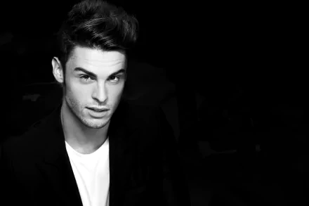 Black and white 4K ultra HD portrait of French male model Baptiste Giabiconi against a dark background, captured with striking contrast and sharp detail.