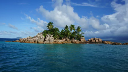 HD desktop wallpaper showing a tropical island in Seychelles with palm trees, rocky shores, and clear ocean waters under a partly cloudy sky.