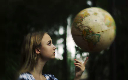 HD desktop wallpaper of a blonde woman in profile, focused on a glowing globe with a bokeh background, creating a thoughtful and contemplative mood.
