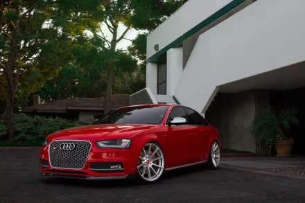 HD desktop wallpaper featuring a red Audi S4 parked near a modern building, surrounded by greenery.