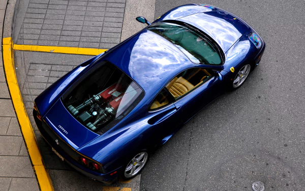 A sleek blue Ferrari 360 Modena supercar parked on a street, captured from above, showcased as an HD PC desktop wallpaper and background.